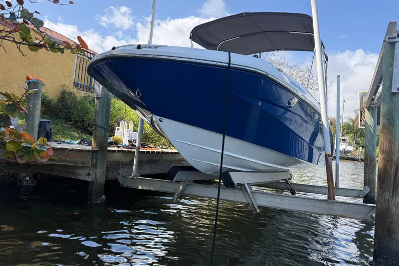 Slide: The Image of 2023 Hurricane SunDeck Sport 205 OB boat docked on a lift by the water. - 8