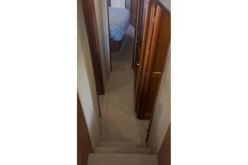 Slide: The Image of Narrow hallway inside 1998 Ocean 53 Convertible yacht, featuring wooden cabinetry and carpeted flooring. - 20