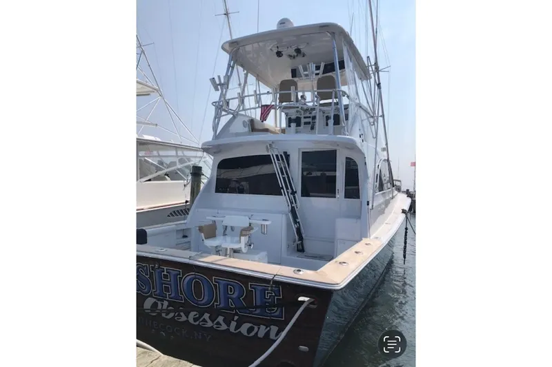 Slide: The Image of 1998 Ocean 53 Convertible yacht docked, featuring a spacious deck and flybridge. - 6