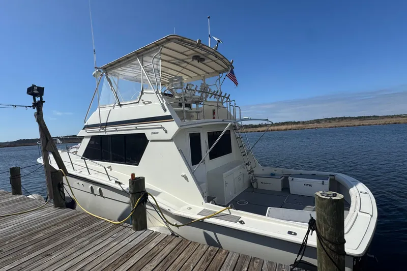 Slide: The Image of 1990 Hatteras 52 Convertible yacht docked by the water on a sunny day. - 19