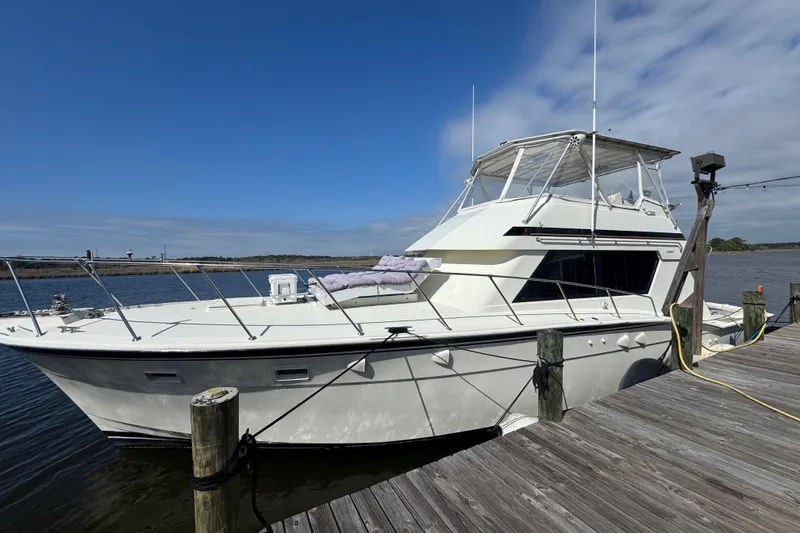Slide: The Image of 1990 Hatteras 52 Convertible yacht docked by a wooden pier under a clear blue sky. - 20