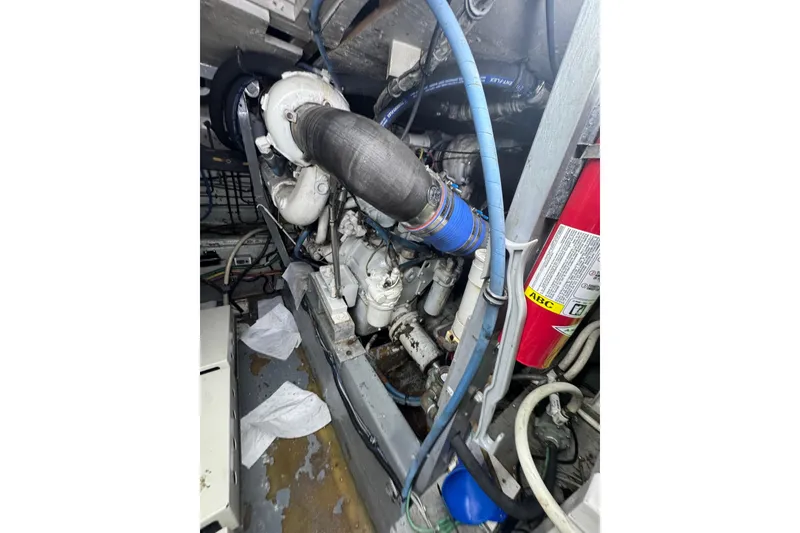 Slide: The Image of Engine room of 1990 Hatteras 52 Convertible boat, showcasing mechanical components and hoses. - 25