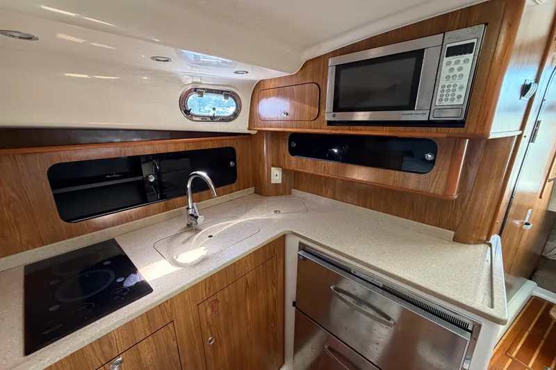 Slide: The Image of 2009 Pursuit OS 375 Offshore yacht kitchen with microwave, sink, and stovetop. - 17