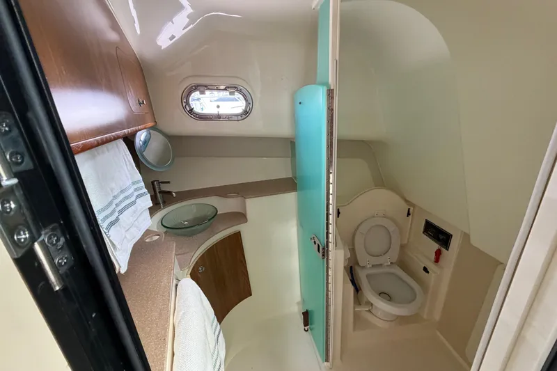 Slide: The Image of 2009 Pursuit OS 375 Offshore boat bathroom with sink, toilet, and porthole window. - 19