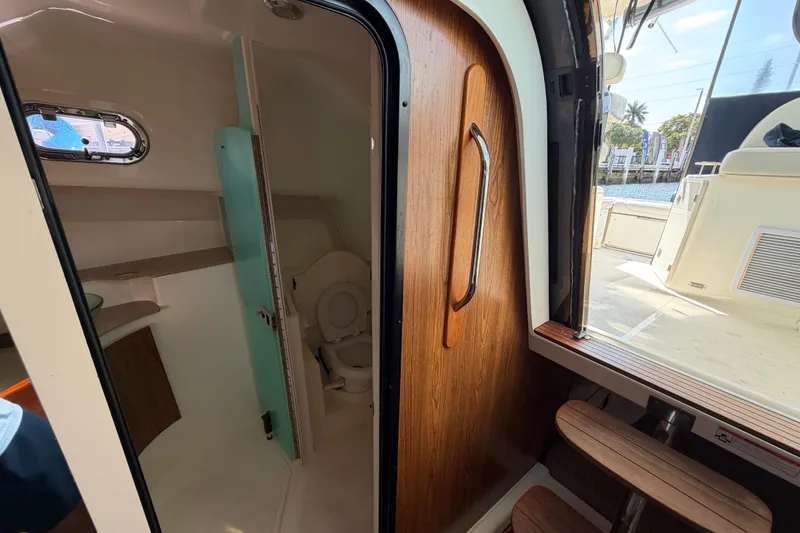 Slide: The Image of Interior view of 2009 Pursuit OS 375 Offshore boat bathroom with wooden door and window. - 21