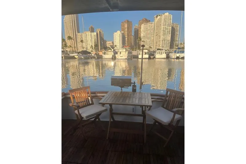 Slide: The Image of 1979 Cheoy Lee Sedan 35 yacht with marina view, featuring outdoor seating and city skyline. - 7