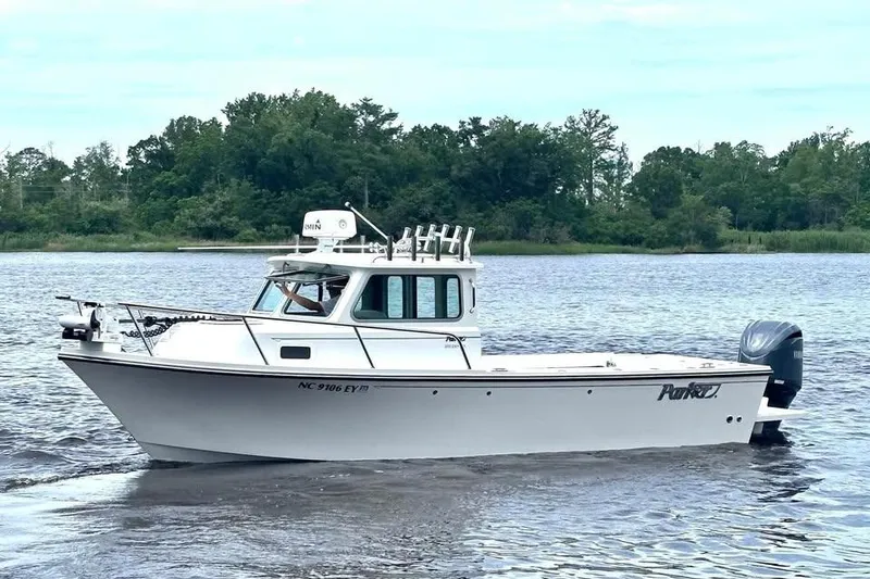 The Image of 2022 Parker 2320 Sport Cabin boat on a calm river with lush green background. - 0