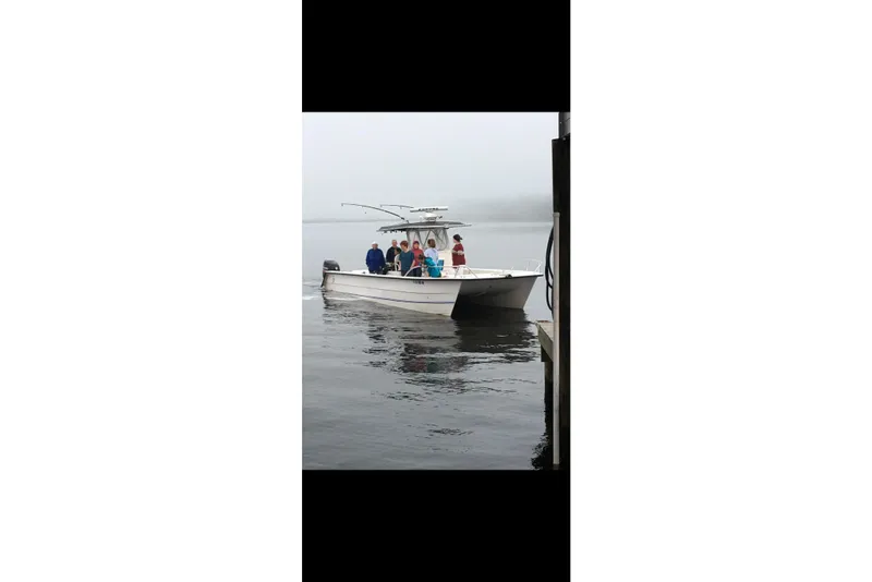 Slide: The Image of 2006 Twin Vee 36 Center Console boat with passengers near a dock on a foggy day. - 27