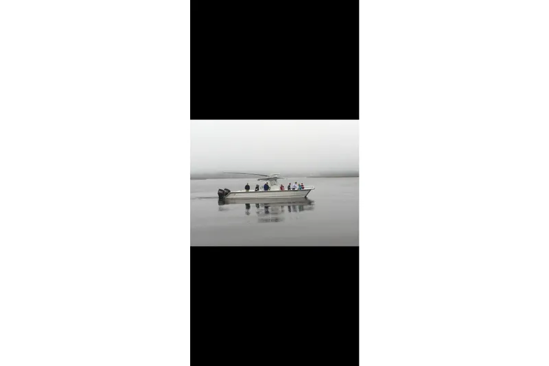 Slide: The Image of 2006 Twin Vee 36 Center Console boat on calm, foggy water with passengers. - 30
