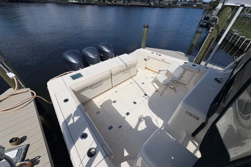 Slide: The Image of 2011 Pursuit OS 375 Offshore boat with triple outboard motors docked by the water. - 13