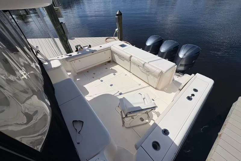 Slide: The Image of 2011 Pursuit OS 375 Offshore boat with triple outboard motors docked by the water. - 14