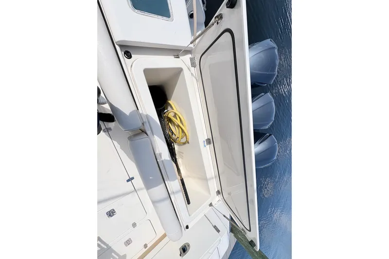Slide: The Image of 2011 Pursuit OS 375 Offshore boat storage compartment with yellow hose and net. - 22