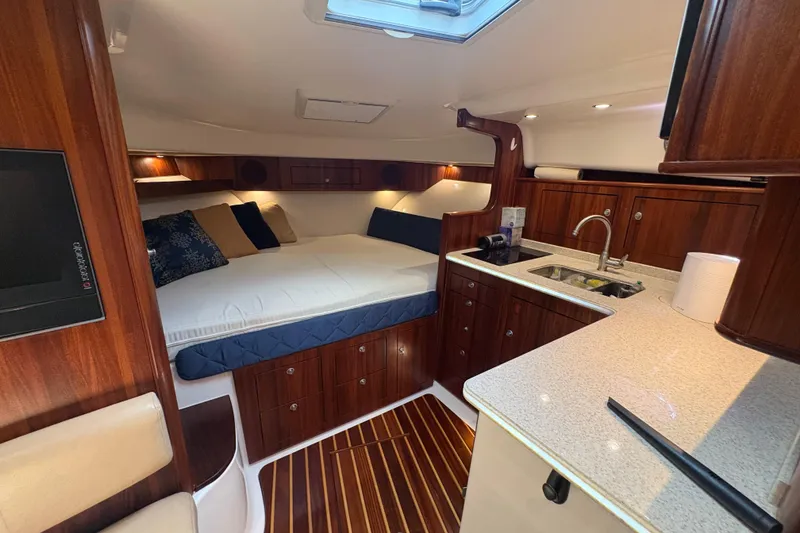 Slide: The Image of Luxurious interior of a 2011 Pursuit OS 375 Offshore boat with wood finishes and cozy bedding. - 38