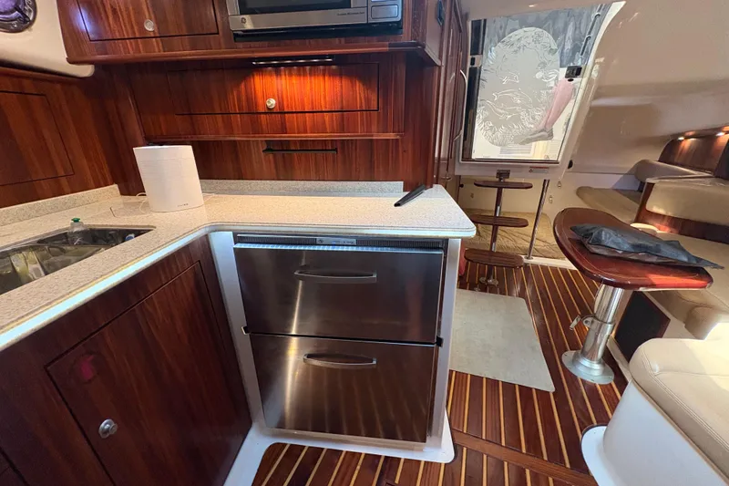 Slide: The Image of Interior of a 2011 Pursuit OS 375 Offshore boat with wood cabinetry and stainless steel appliances. - 40
