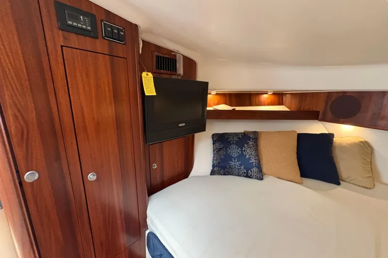 Slide: The Image of 2011 Pursuit OS 375 Offshore cabin with wood paneling, TV, and cozy bedding. - 45