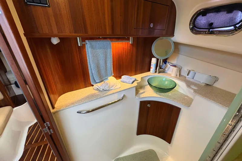 Slide: The Image of 2011 Pursuit OS 375 Offshore bathroom with wooden cabinetry and glass sink. - 47