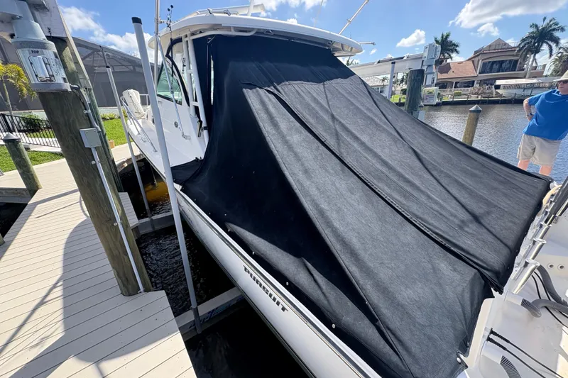 Slide: The Image of 2011 Pursuit OS 375 Offshore boat docked with black cover, sunny day, waterfront view. - 5