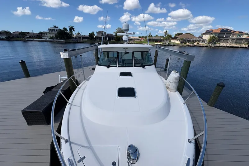 Slide: The Image of 2011 Pursuit OS 375 Offshore boat docked by waterfront homes under blue sky. - 7