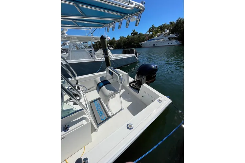 Slide: The Image of 1995 Contender 21 CC boat docked on calm water, featuring a sleek design and outboard motor. - 5