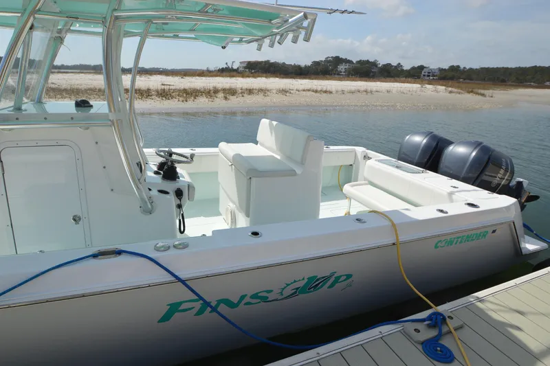 Slide: The Image of 2015 Contender 32 ST boat docked by sandy shore with dual outboard motors. - 11