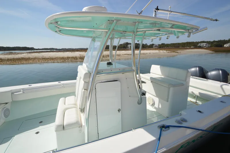 Slide: The Image of 2015 Contender 32 ST boat with T-top, docked near a sandy shoreline. - 15