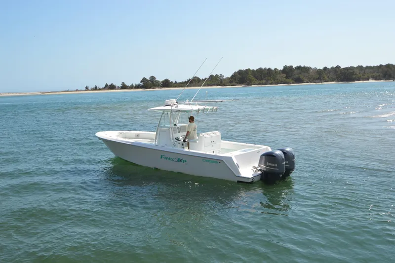 Slide: The Image of 2015 Contender 32 ST boat on calm water near a sandy shoreline. - 5