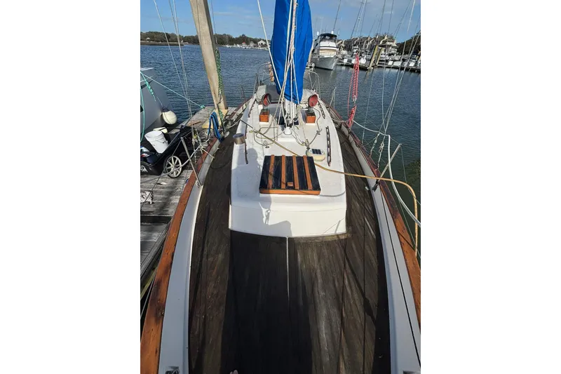 Slide: The Image of 1977 Pacific Seacraft 31 sailboat docked at marina, featuring wooden deck and blue sail cover. - 3