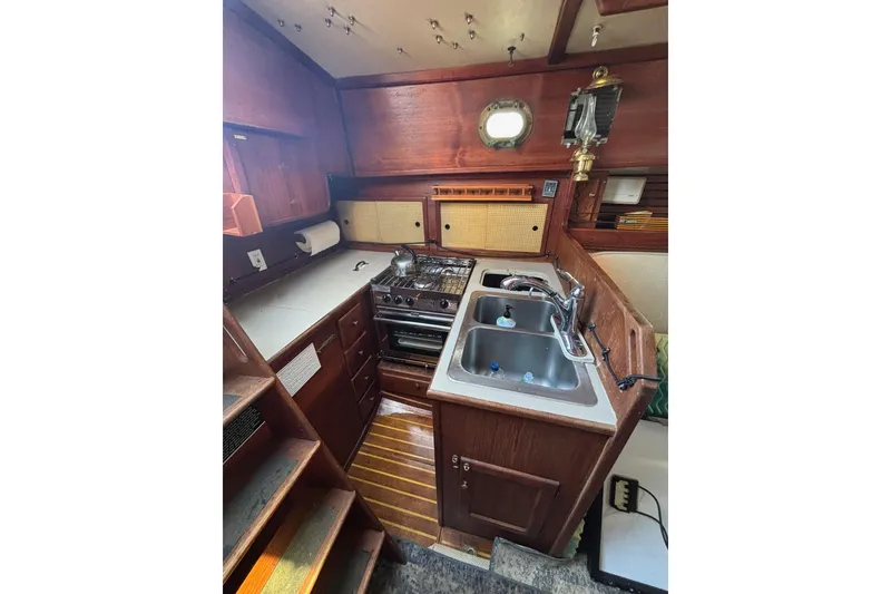 Slide: The Image of Interior of 1977 Pacific Seacraft 31 sailboat galley with stove, sink, and wooden cabinetry. - 4