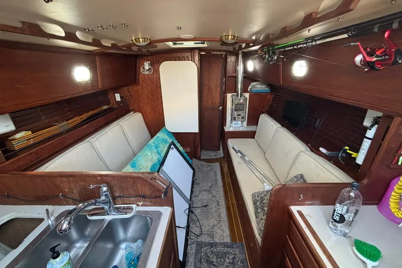 Slide: The Image of Interior of a 1977 Pacific Seacraft 31 sailboat with cozy seating and wooden finishes. - 5