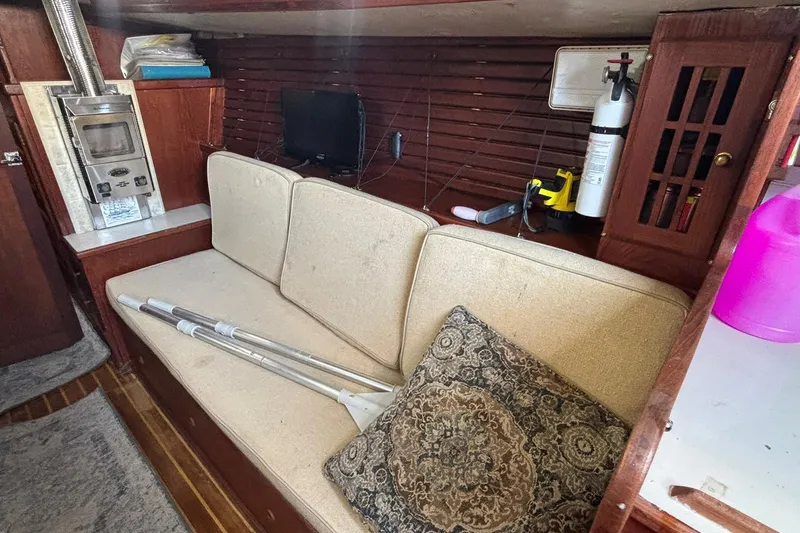Slide: The Image of Interior of a 1977 Pacific Seacraft 31 sailboat with cozy seating and wood paneling. - 7