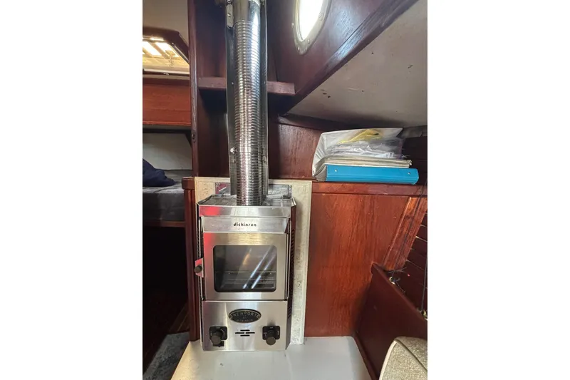 Slide: The Image of Dickinson stove inside 1977 Pacific Seacraft 31 sailboat cabin, with wooden interior. - 9