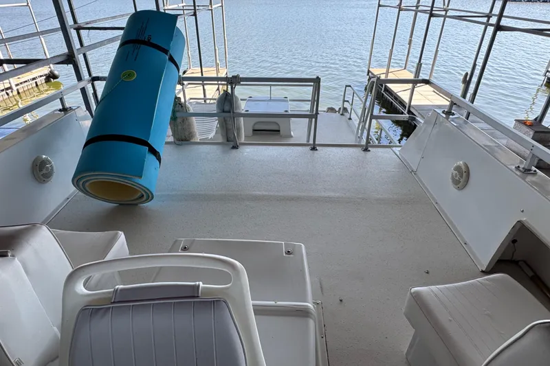 Slide: The Image of 1993 Gibson 44 Cabin Yacht deck with seating and rolled mat, docked by the water. - 62