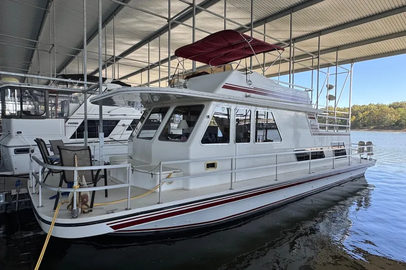 The Image of 1993 Gibson 44 Cabin Yacht docked under a covered marina, featuring a spacious deck. - 2