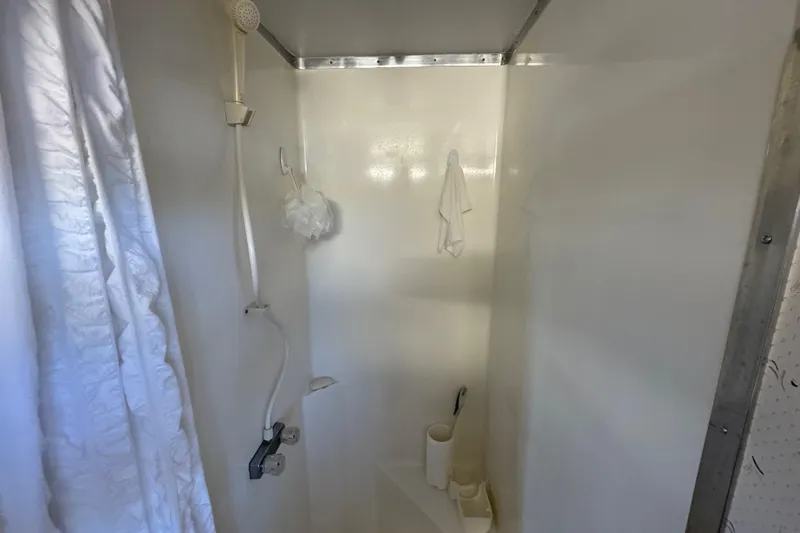 Slide: The Image of Shower area inside 1993 Gibson 44 Cabin Yacht, featuring white walls and showerhead. - 28