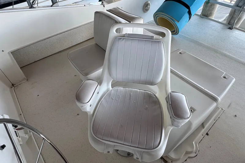 Slide: The Image of White captain's chair on 1993 Gibson 44 Cabin Yacht deck, with blue mat nearby. - 58