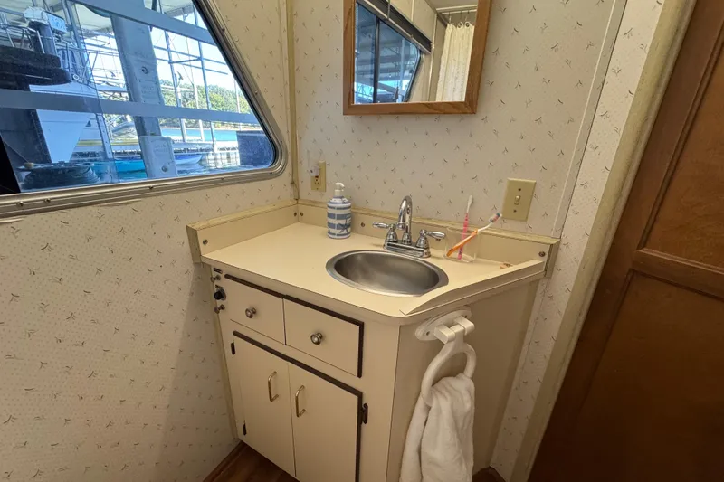 Slide: The Image of Bathroom sink area in a 1993 Gibson 44 Cabin Yacht with mirror and window view. - 27