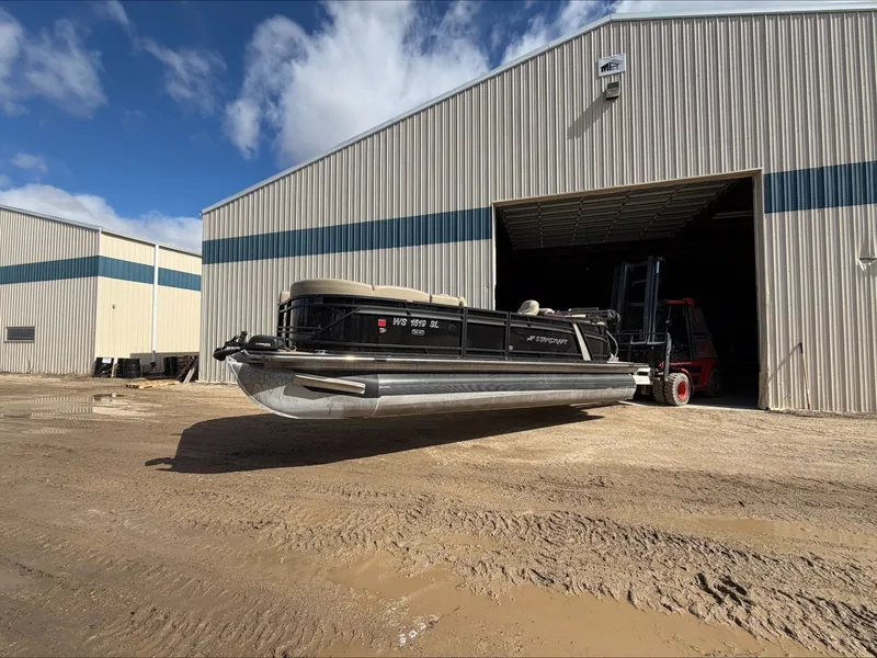 Slide: The Image of 2023 Starcraft SLS 3 pontoon boat outside warehouse. - 4