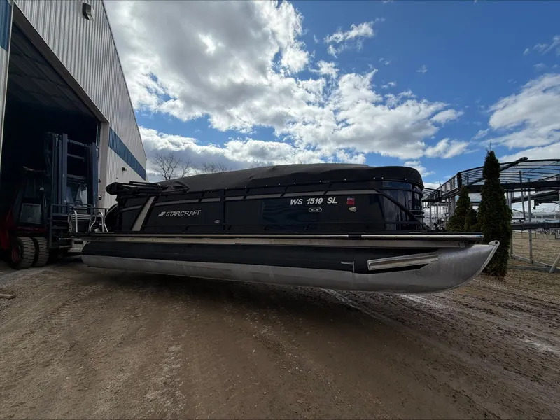 Slide: The Image of 2023 Starcraft SLS 3 pontoon boat outside warehouse. - 7