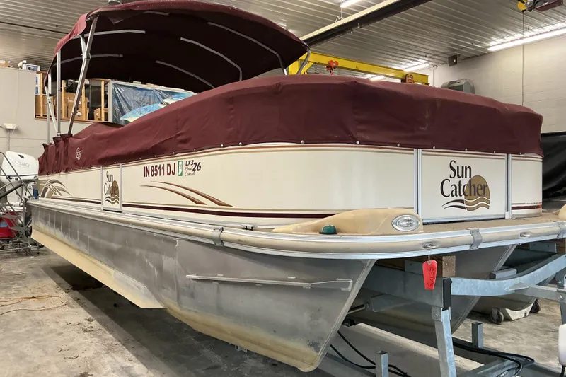 Slide: The Image of 2008 SunCatcher LX3 26 DC pontoon boat with maroon cover in indoor storage. - 10