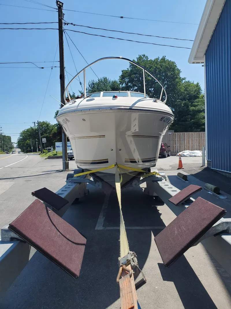 Slide: The Image of 2001 Sea Ray 245 Weekender boat on trailer, parked outdoors near a blue building. - 4
