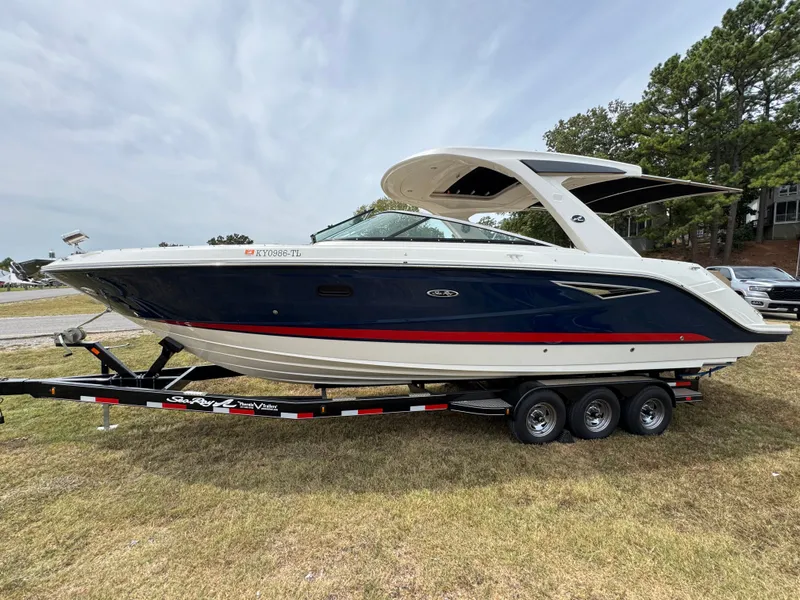Slide: The Image of 2022 Sea Ray SLX 310 boat on trailer, parked on grass, side view. - 2