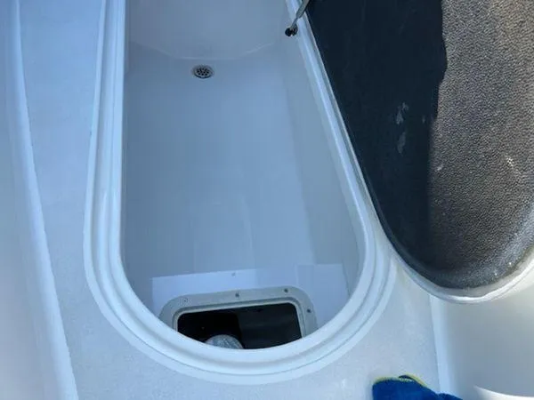 Slide: The Image of Open storage compartment in a 2008 Spectre 34 boat, featuring a drain and black cover. - 39
