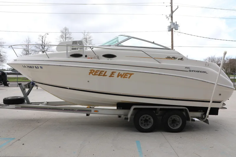 Slide: The Image of 1998 Searay Sundancer boat on trailer, named "Reel E Wet," parked outdoors. - 4