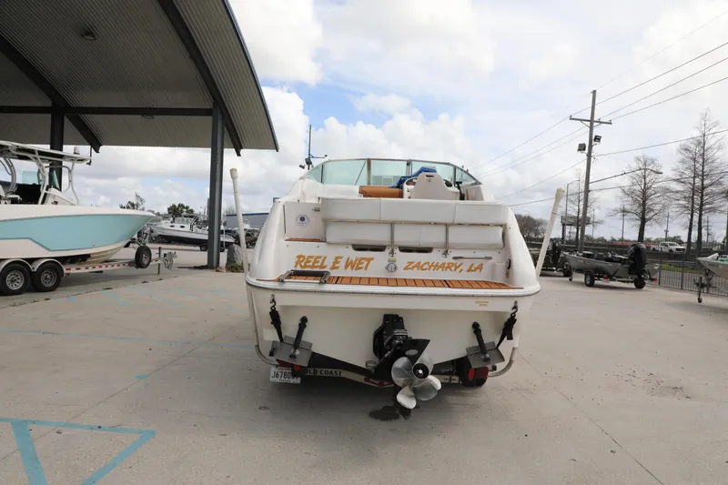 Slide: The Image of 1998 Searay Sundancer boat at marina, rear view with "Reel E Wet" text. - 6