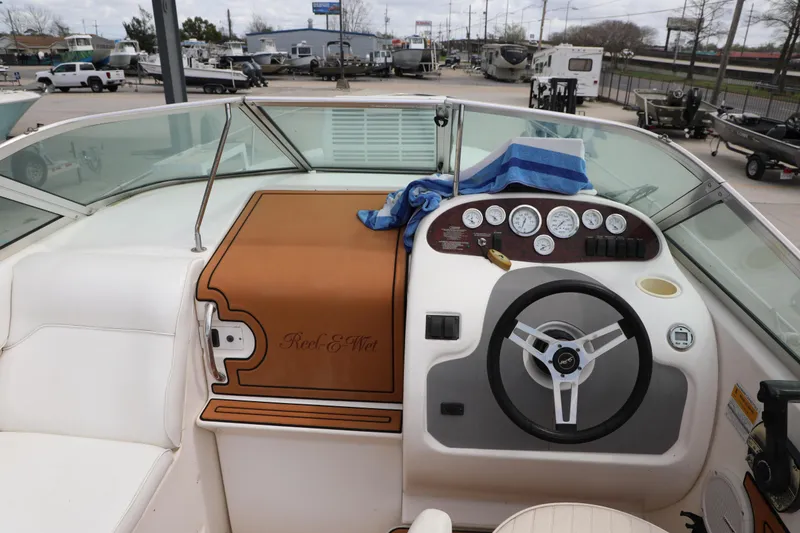 Slide: The Image of 1998 Searay Sundancer boat dashboard with steering wheel and gauges, docked outdoors. - 9