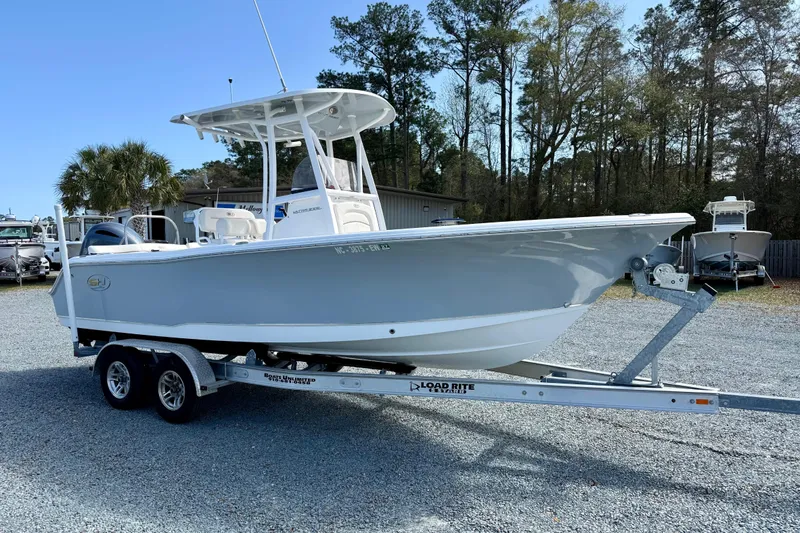 The Image of 2022 Sea Hunt Ultra 229 boat on trailer, parked outdoors with trees in background. - 0