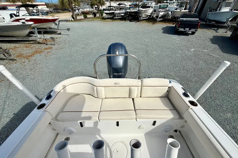 Slide: The Image of 2022 Sea Hunt Ultra 229 boat interior with helm, rod holders, and T-top under blue sky. - 16