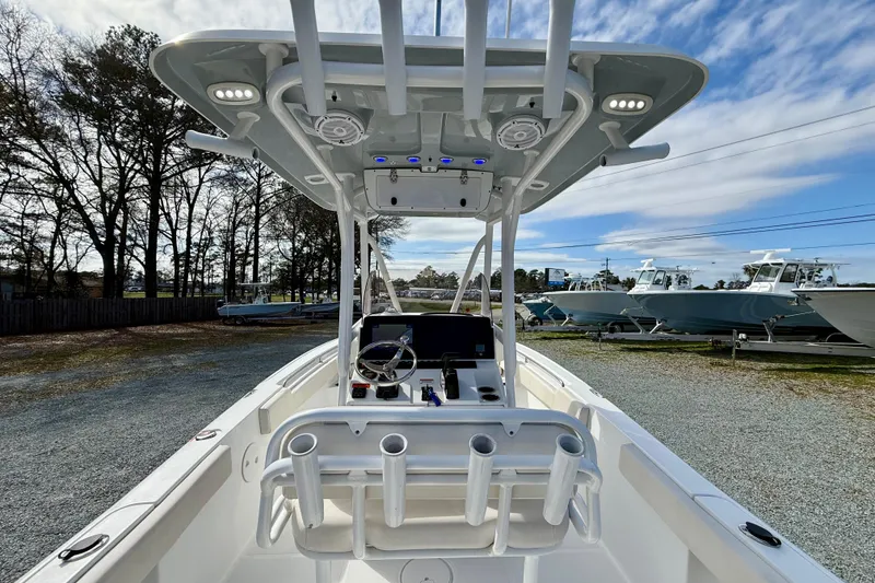 Slide: The Image of 2022 Sea Hunt Ultra 229 boat with center console and rod holders, parked outdoors. - 17