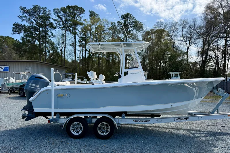Slide: The Image of 2022 Sea Hunt Ultra 229 boat on trailer, parked outdoors under clear blue sky. - 8