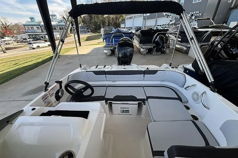 Slide: The Image of 2024 Bayliner Element M17 boat interior with seating and steering wheel, docked outdoors. - 14